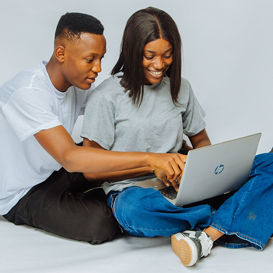 Female student showing male classmate something interesting on her laptop screen