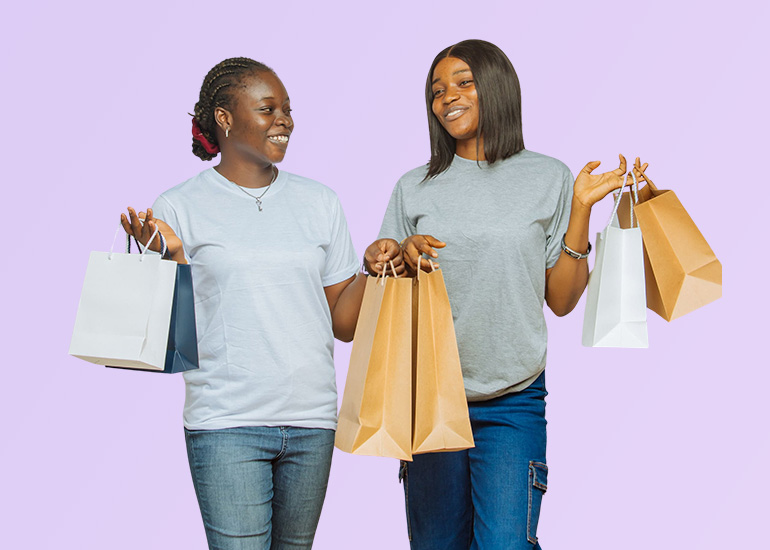 Two female students showing shopping bags celebrates their student deals